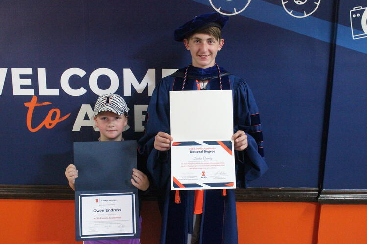 Two kids hold diplomas 