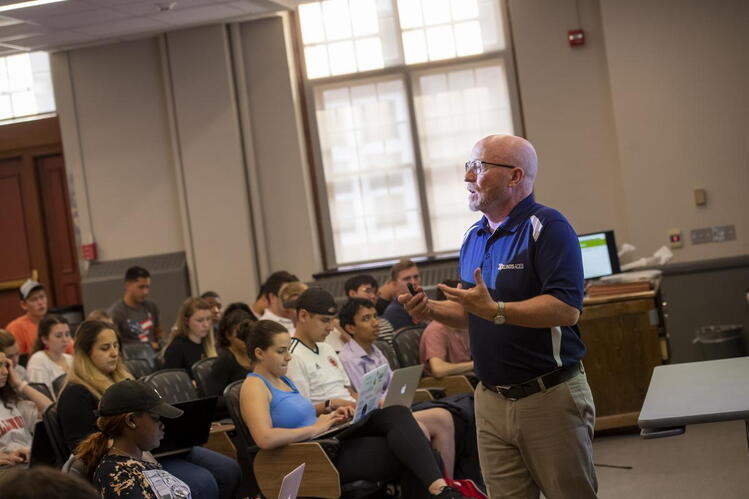Paul Stoddard teaching in front of a lecture hall. 