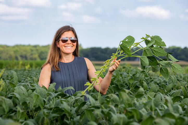 Lisa Ainsworth stands in a crop field wearing sunglasses