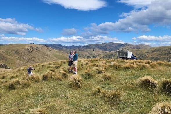 Bob Hauser, Mark Stevenson, and Mark's son Ted stand on a scenic New Zealand ranch