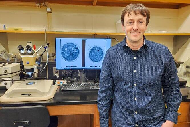 Nathan Schroeder standing in front of a computer screen in a lab