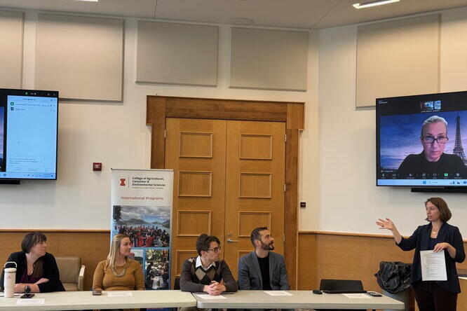 four people at table with moderator standing 