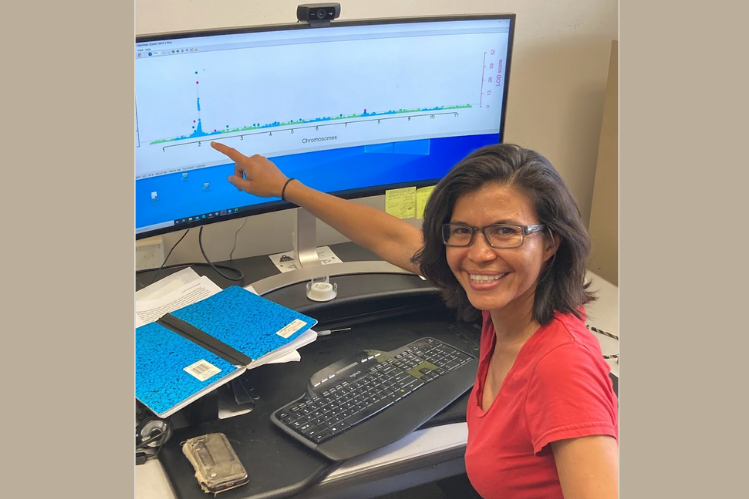 Woman pointing to a computer monitor showing a graph with a large peak of blue dots in one area