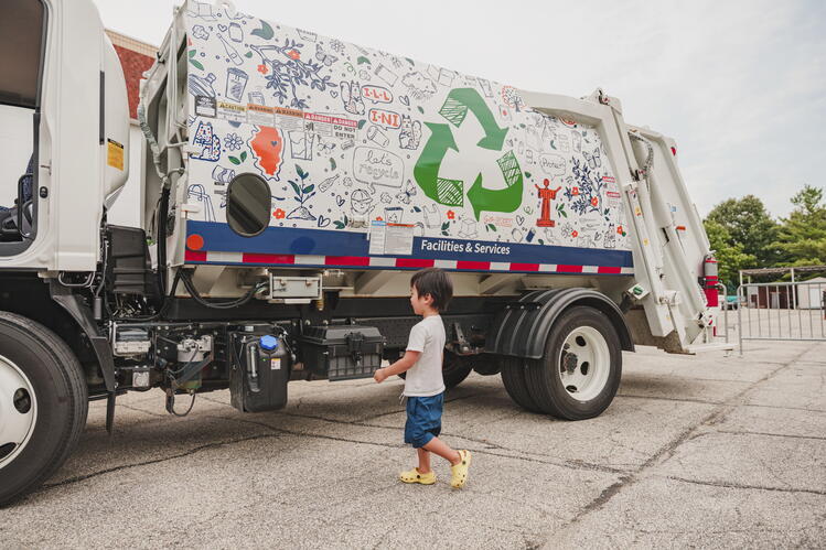 A child stands in front of a large, white truck