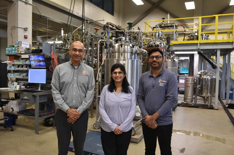 From left to right: Vijay Singh, Mounika Durga Nenavath, Narendra Naik Deshavath. Credit: April Wendling/CABBI Three individuals posing in a laborary environment with large equipment behind them