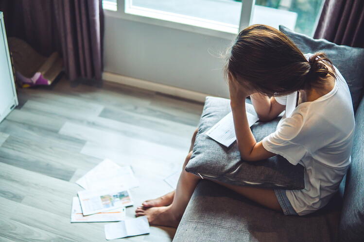 A woman sitting with her head in her hands, looking distressed