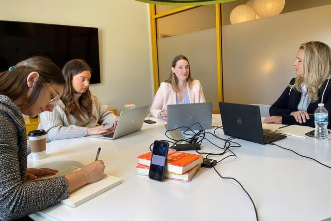 Group of women sitting around a table talking and taking notes