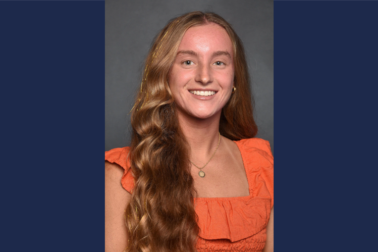 A woman in an orange shirt smiles.