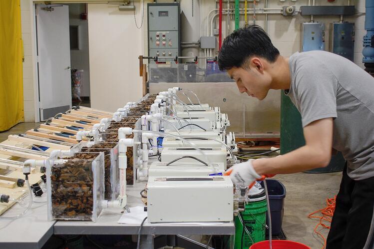 Hongxu Zhou adjusts B2 equipment in the lab A person working on a row of scientific equipment in a laboratory, adjusting settings and observing results.