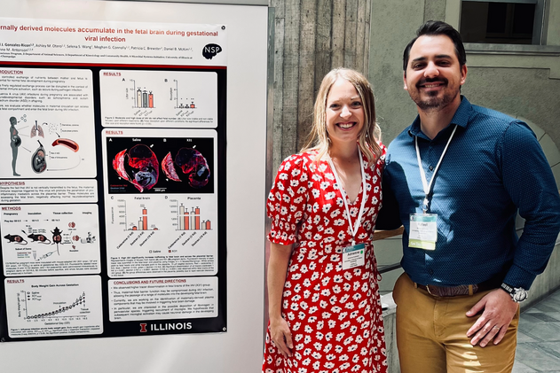 A man and woman stand in front of a research poster