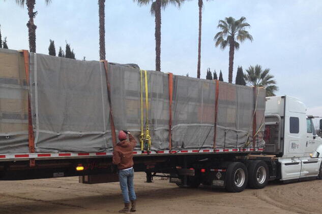 Person standing by semi-truck loaded with bee hives.