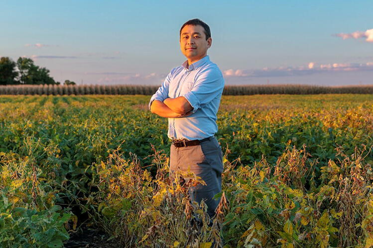 A man stands in a field with his arms crossed