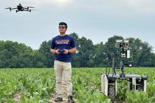 A man wearing sunglasses controlling a drone in a field