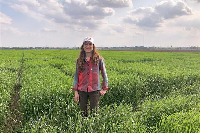Assistant Professor Jessica Rutkoski stands amongst a green field