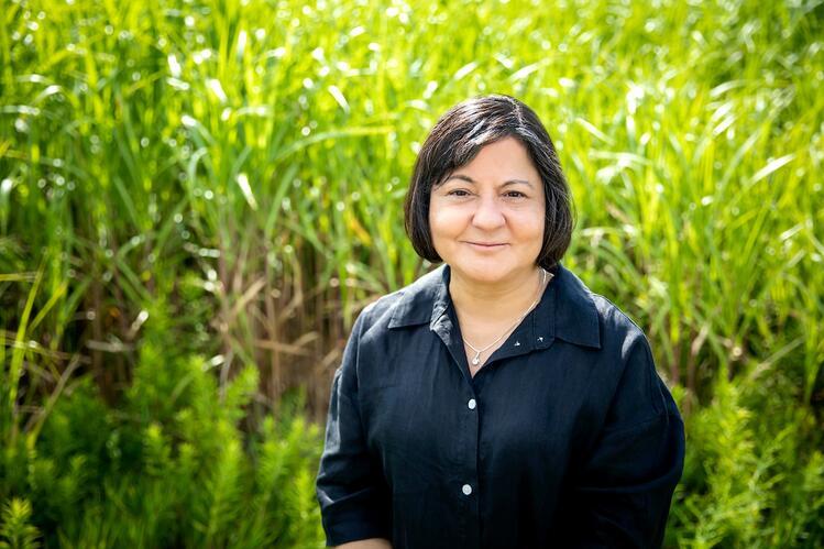 A woman stands in front of a field of crops