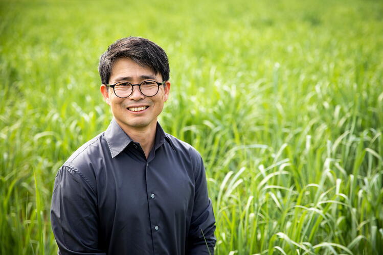 Research leader D.K. Lee A man with glasses and a dark gray shirt stands in front of a field of tall grass