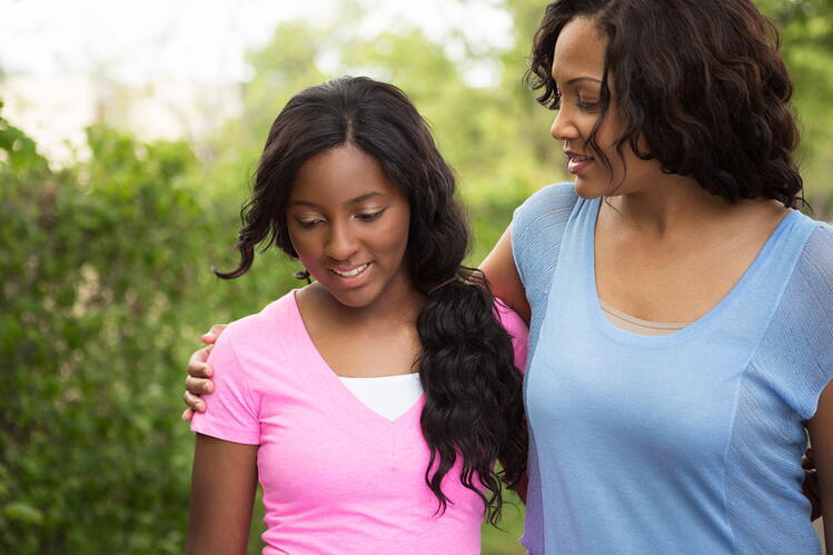 A woman and a teenage girl walking together in an ourdoor setting