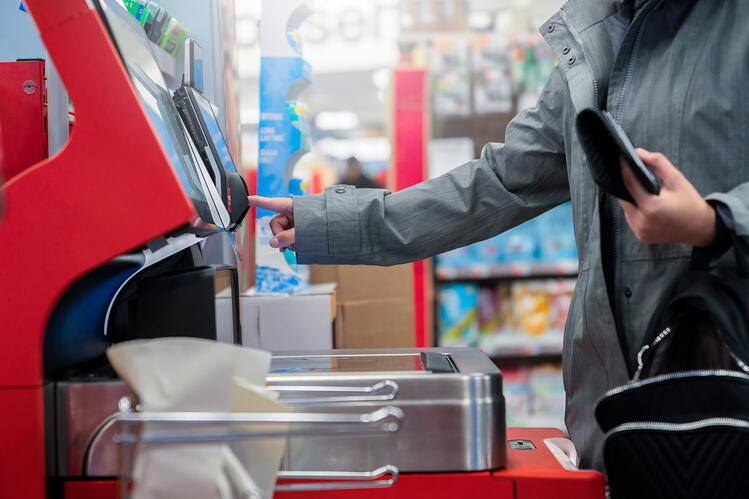 a woman is using a self-checkout register at a grocery store