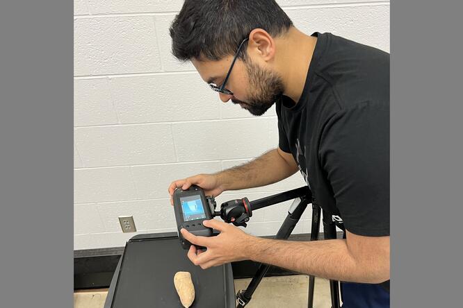 A man takes an image of a sweet potato with a camera in a laboratory setting