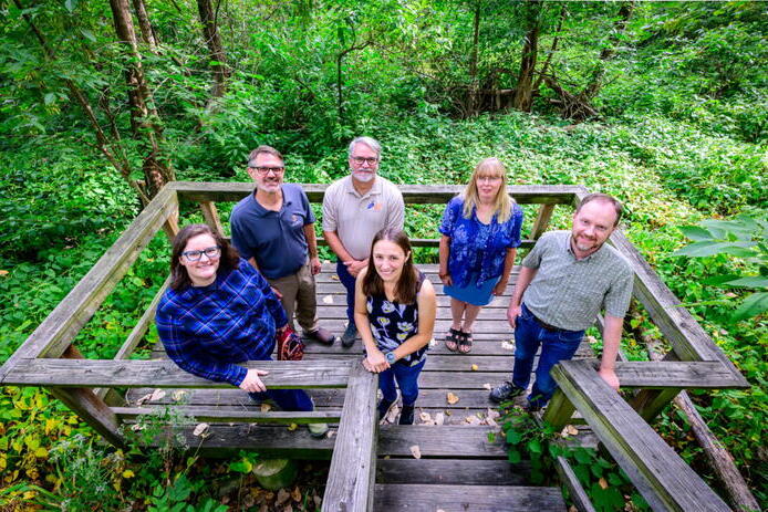 The research team included, clockwise from front center, Chelsea Peterson, Jessica Monson, Geoffrey Pociask, Paul Marcum, Julie Nieset and Jeffrey Matthews. Photo by Fred Zwicky A group of people standing on a wooden structure in a nature setting