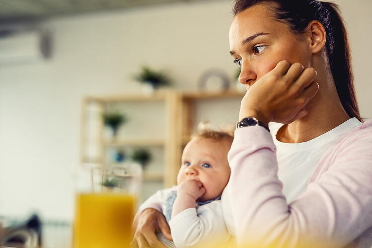 A woman staring into space, holding a baby