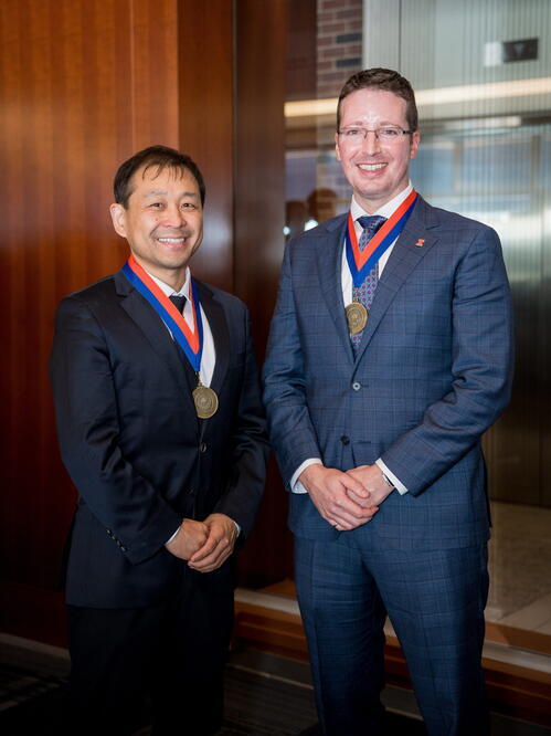 Kaiyu Guan (left) and Jeremy Guest (right) Two men wearing suits and medallions stand together