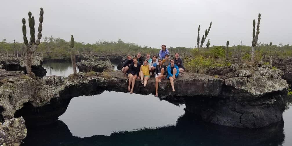 Study abroad students sitting on a rock above a body of water