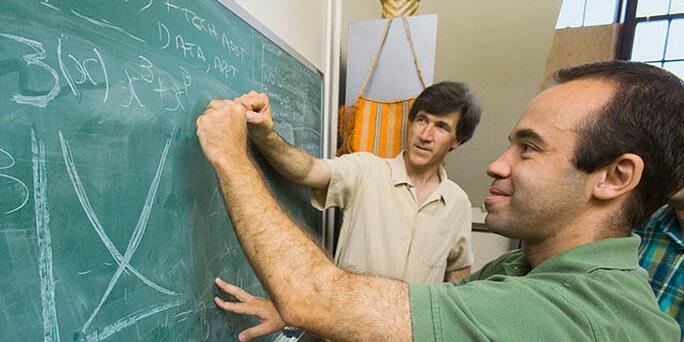 Students writing on a chalkboard