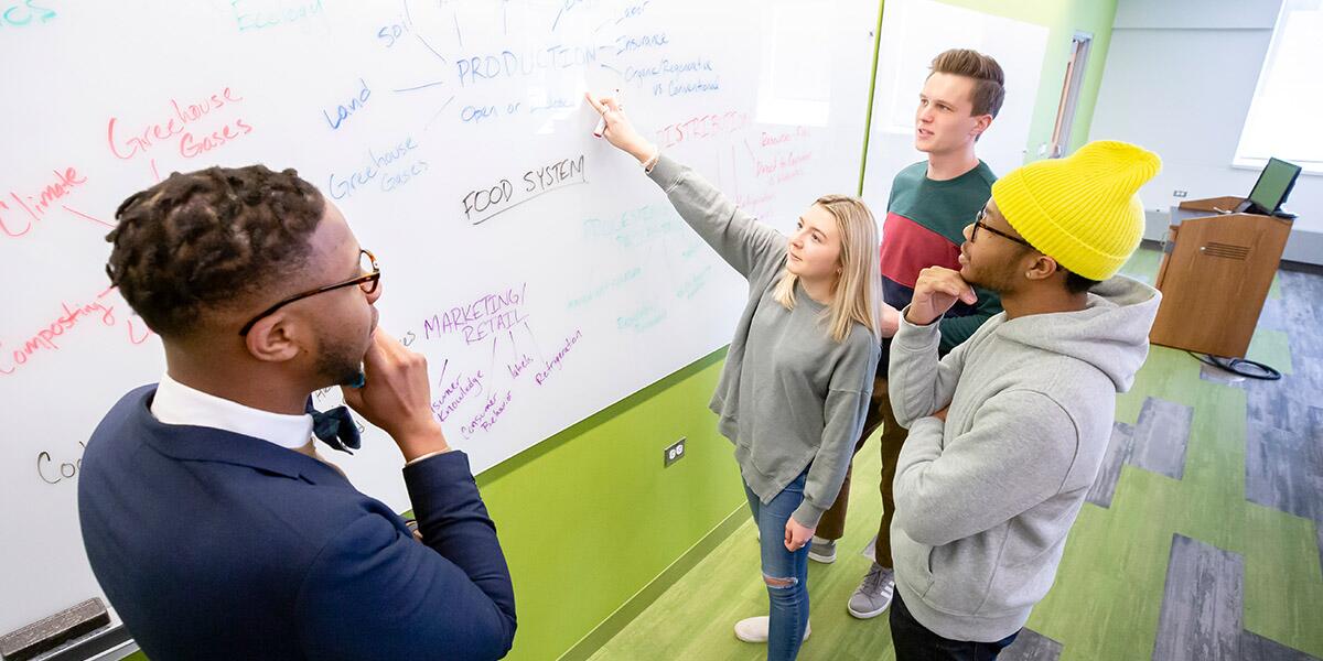 Groups of students brainstorming around a whiteboard.