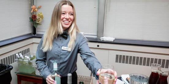 Student serving a glass of wine