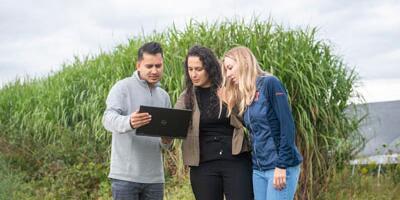 Students in crop field with computer.